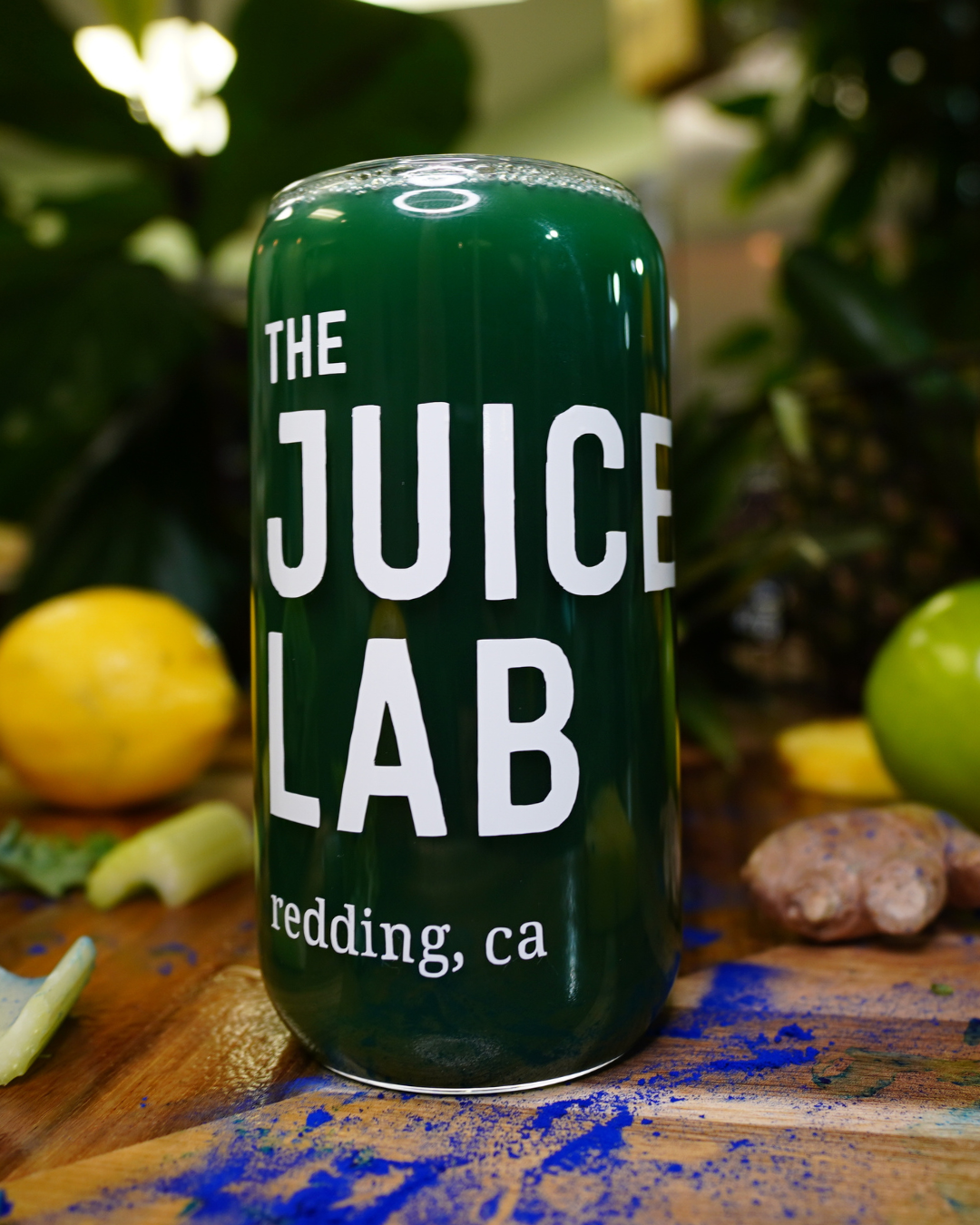 The Juice Lab glass can on wood counter with fresh fruit around